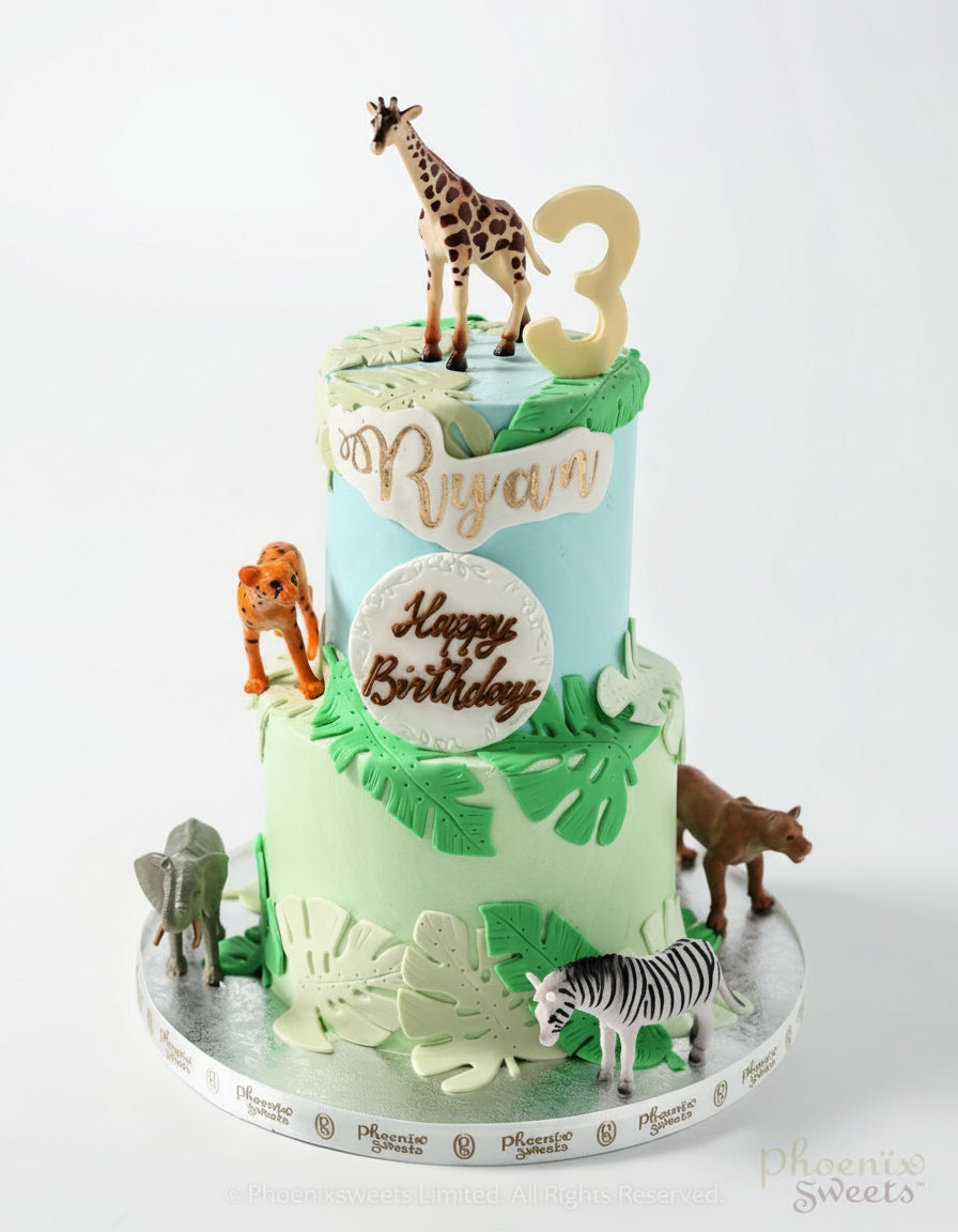 Two-tier birthday cake with animal figurines and 'Happy Birthday' text on a white background